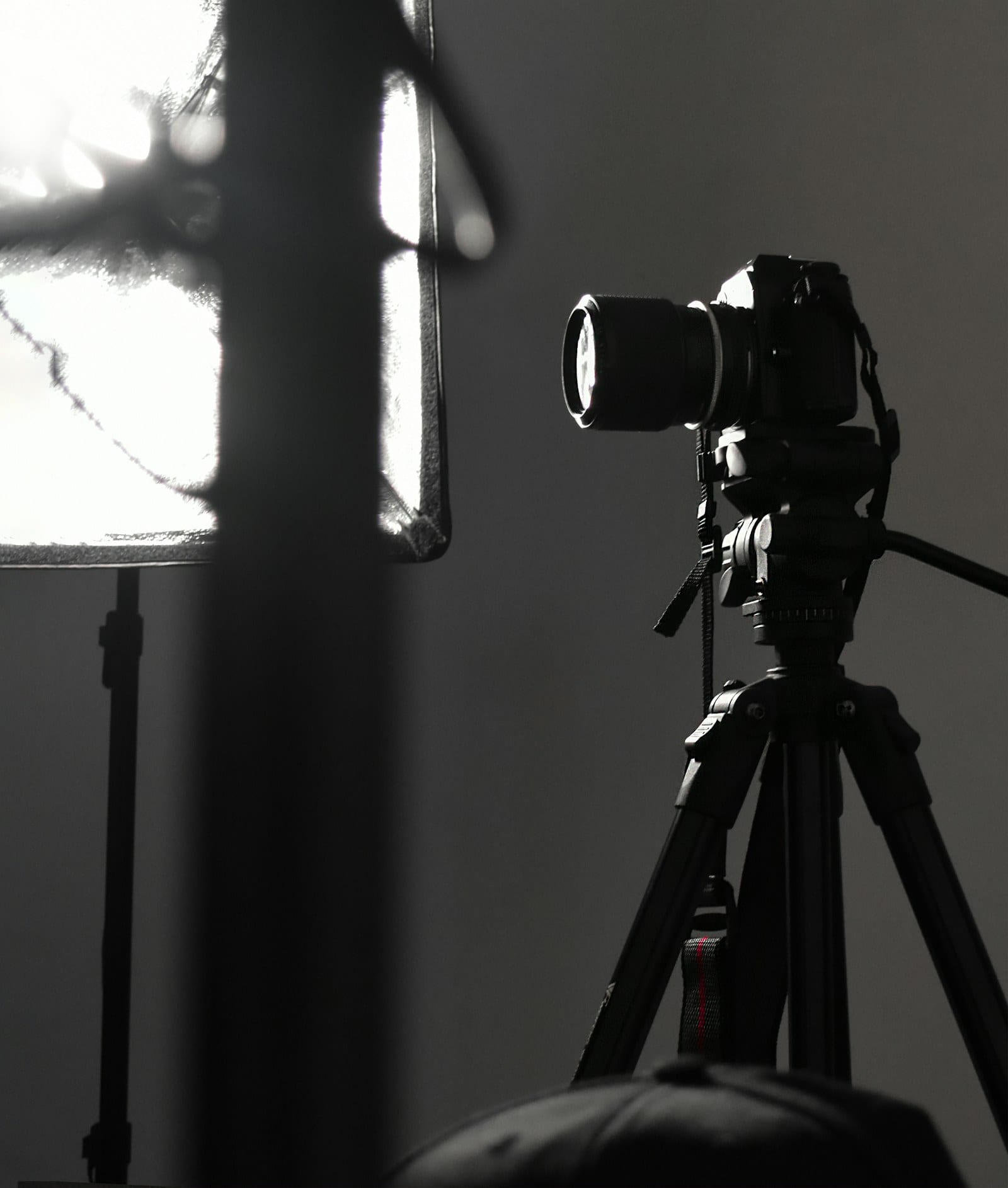 A camera on a tripod by a bright window in a dark studio