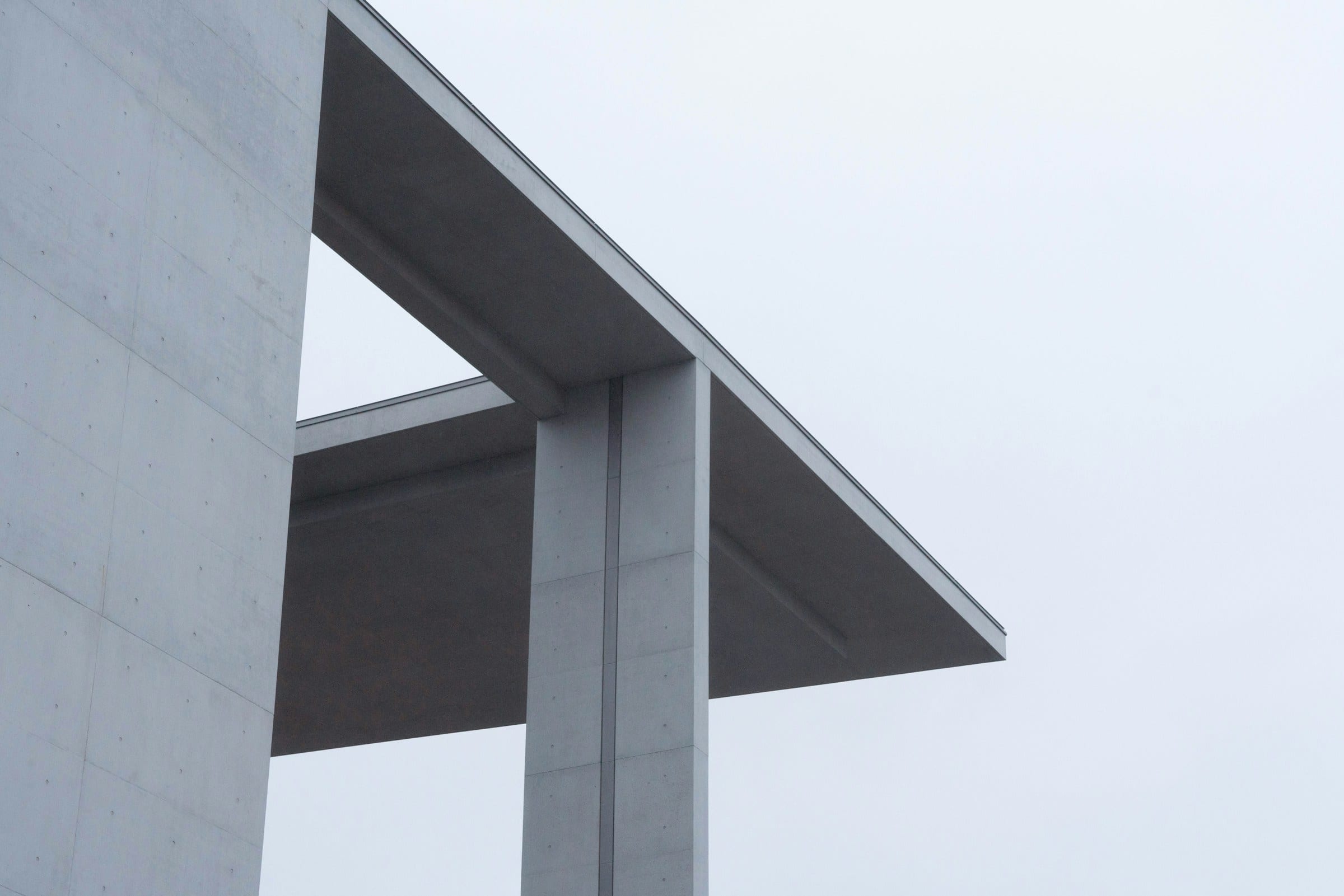 A concrete roof cantilevered out against a pale sky