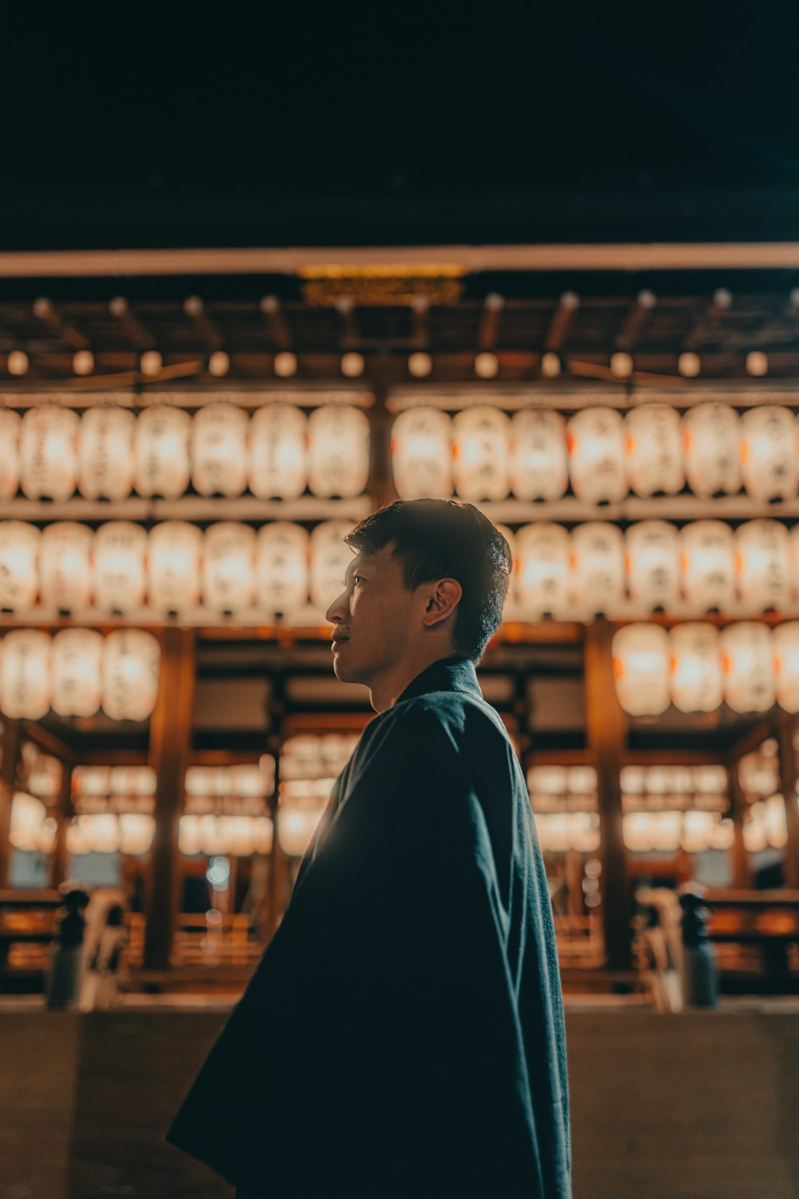 A man standing before a wall of glowing paper lanterns