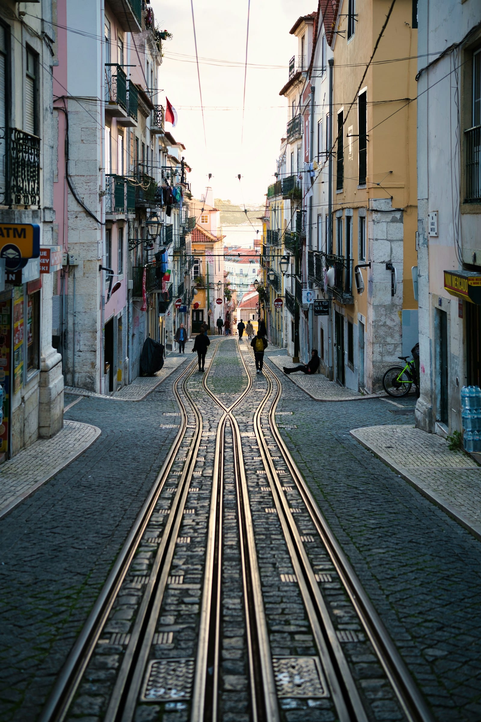 Tram tracks running down a steep, narrow Lisbon street
