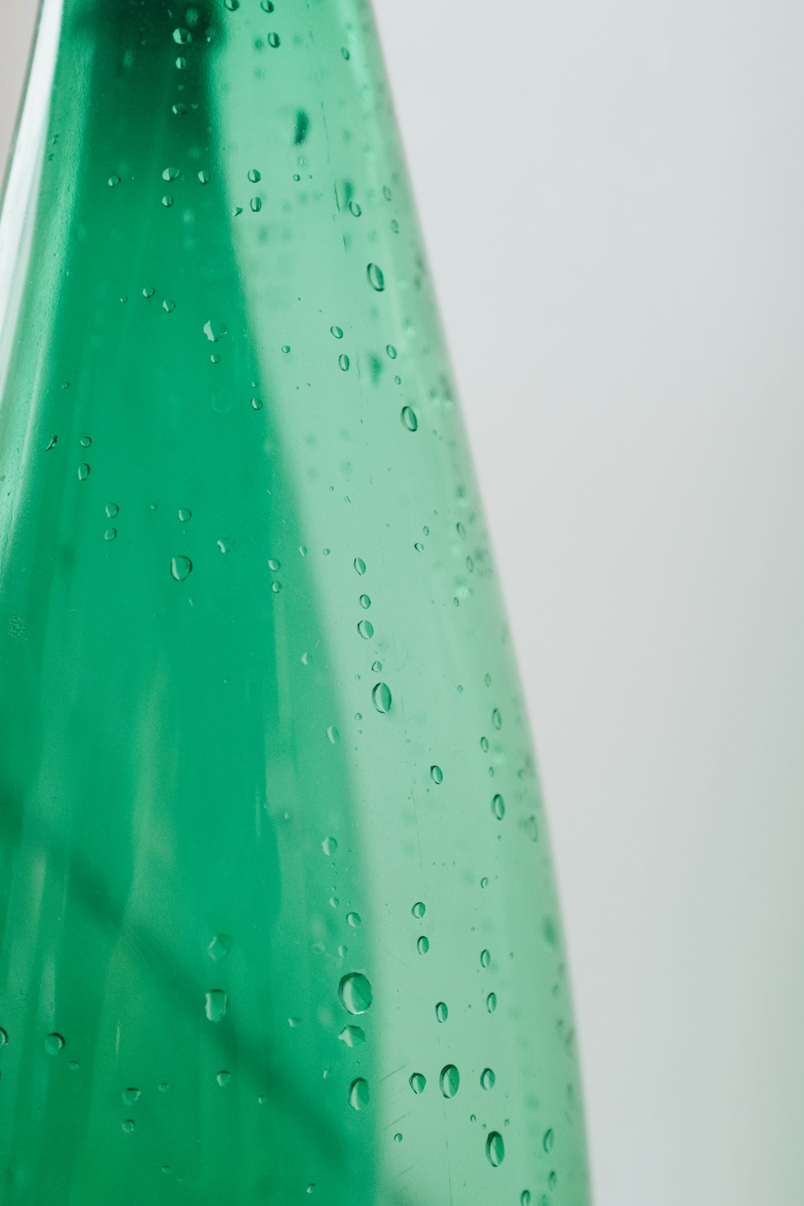 The measured frame: heavy green glass beaded with water droplets, lit from behind