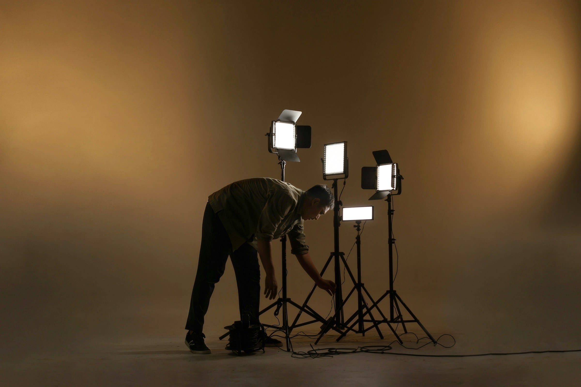 A photographer adjusting a cluster of lights on an empty set before the first frame