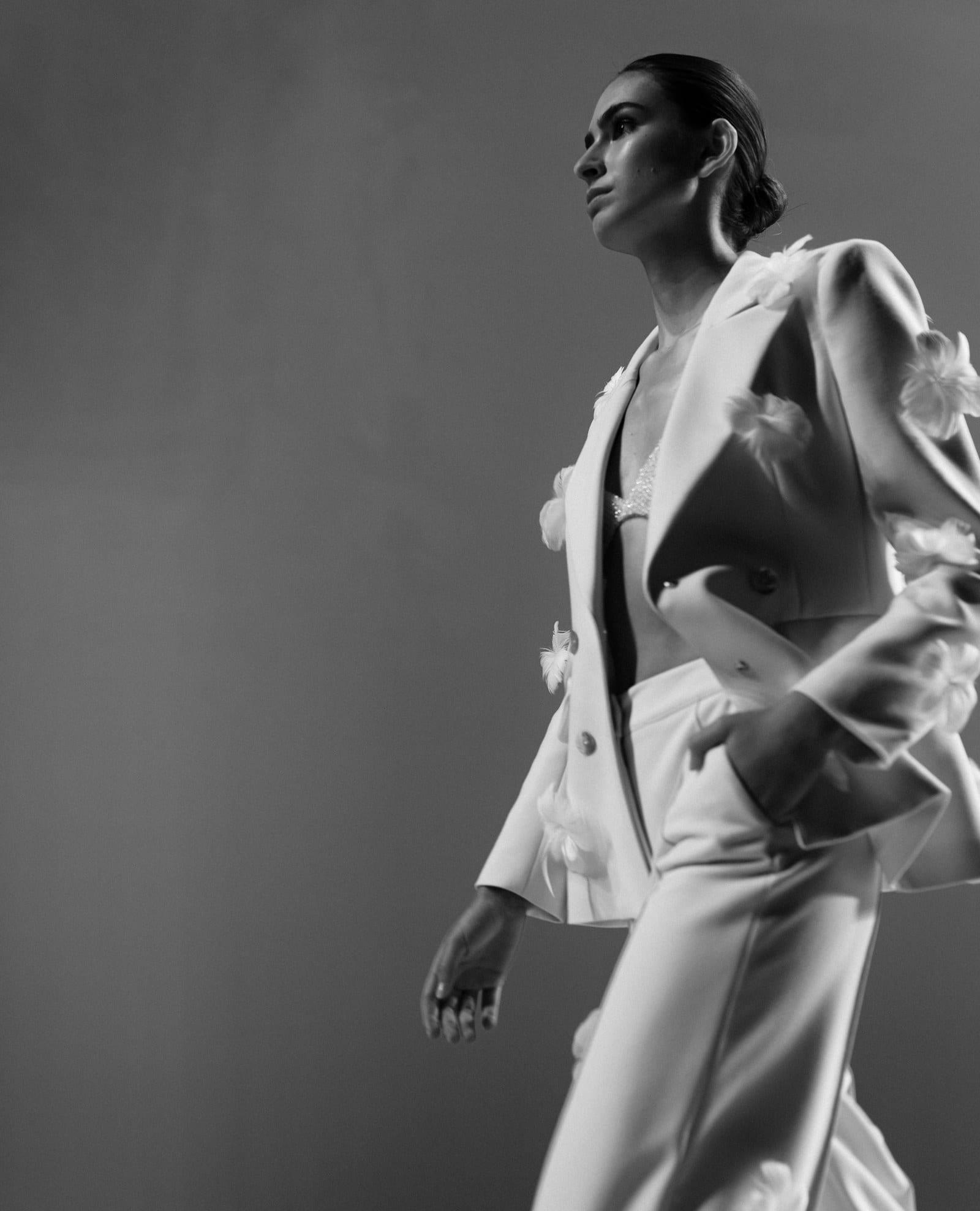 A black and white fashion portrait of a woman in a pale suit